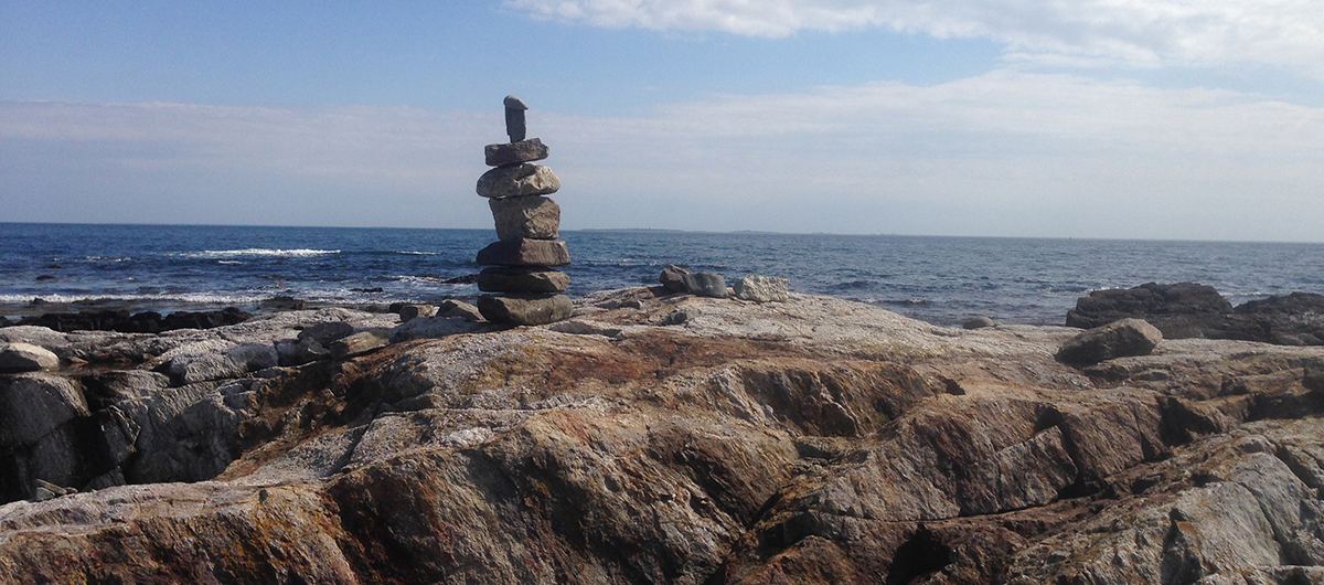 A stone cairn on a rocky shore overlooking the ocean